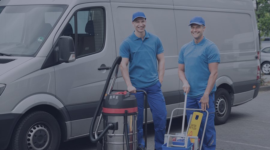 Two men in front of truck with cleaning machines